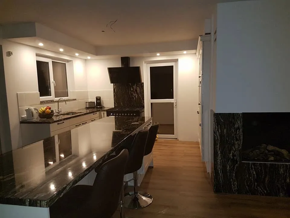 De keuken over de volle lengte, met de bar als scheiding tussen keuken en woonkamer en inbouwspots in de verlaagde koof.