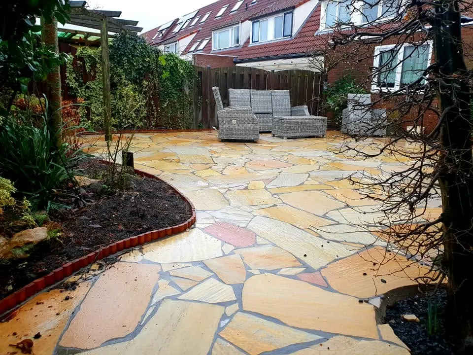 Het terras loopt in een ronde vorm door tot om de boom, met een border langs de rand die is afgezet met een gebogen randstrip.