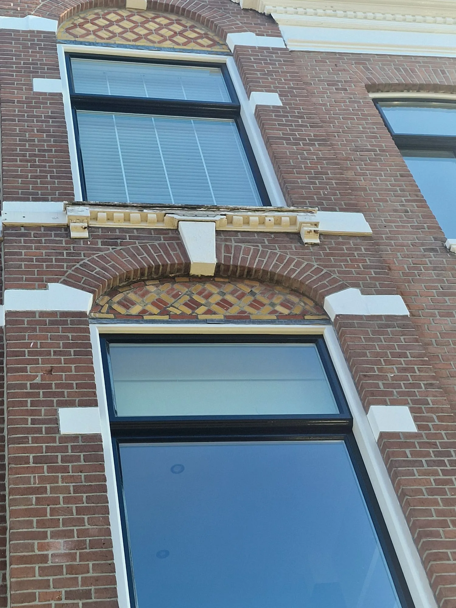 De waterlijst boven de raamboog voor aanvang; de verf laat los en het profiel is op meerdere plekken weggerot.