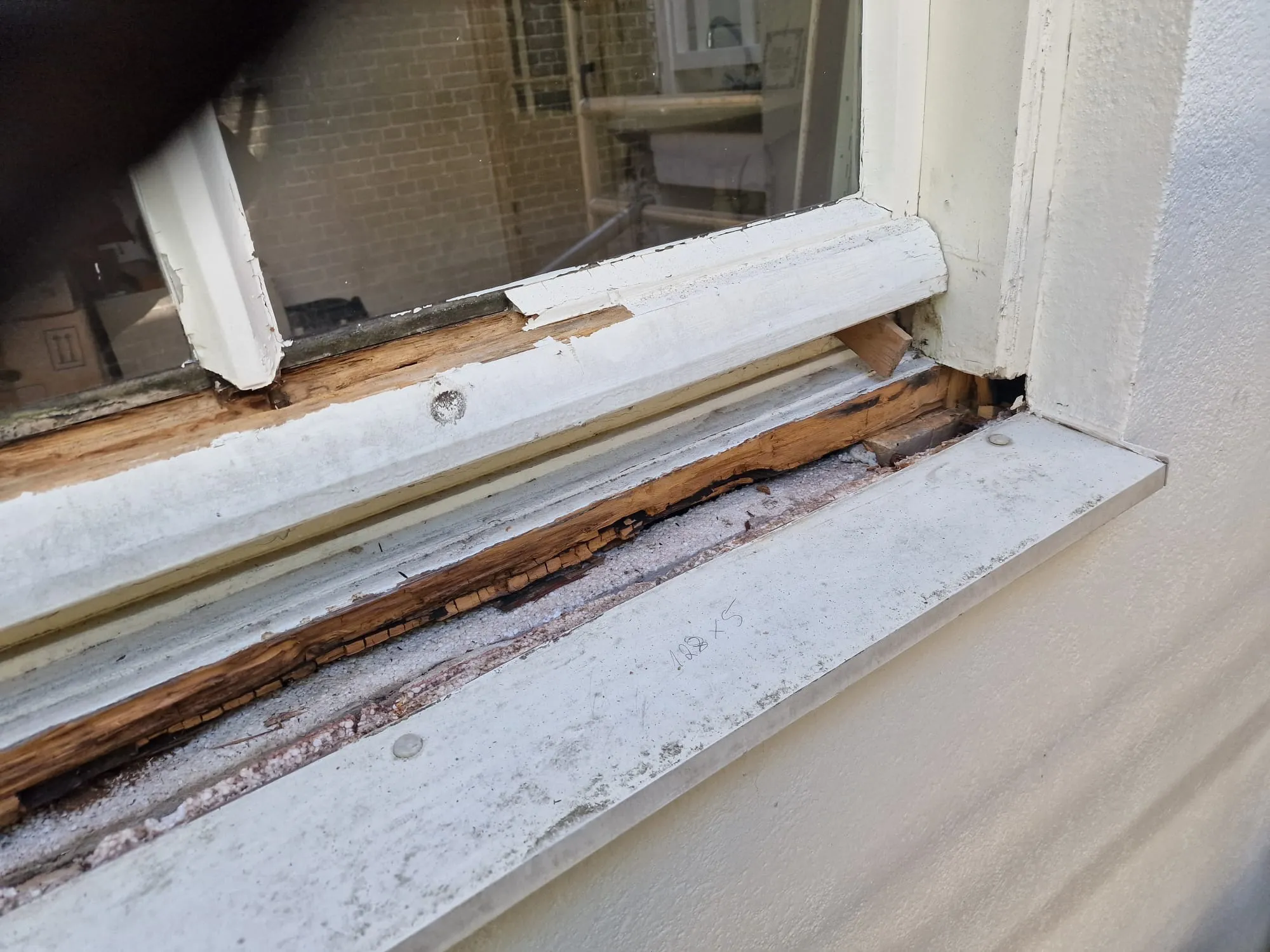 De onderdorpel voor aanvang; de verf is losgekomen en het hout eronder is over de volle lengte vezelig geworden.
